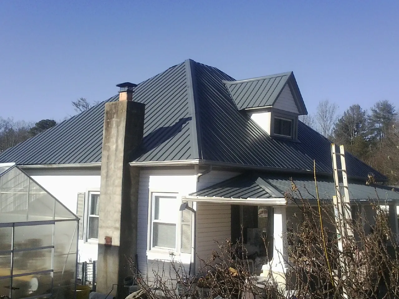 Dark blue standing seam metal roof on a white farmhouse with dormer — Slate & Tile Roof Repair by Roofing Brothers in Kelso