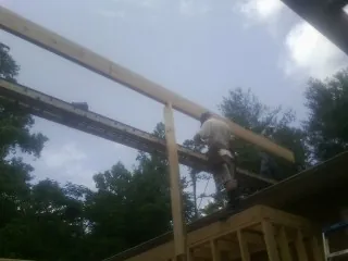 Carpenter setting a ridge beam over a new addition frame — Ice Dam Removal by Roofing Brothers in Kelso