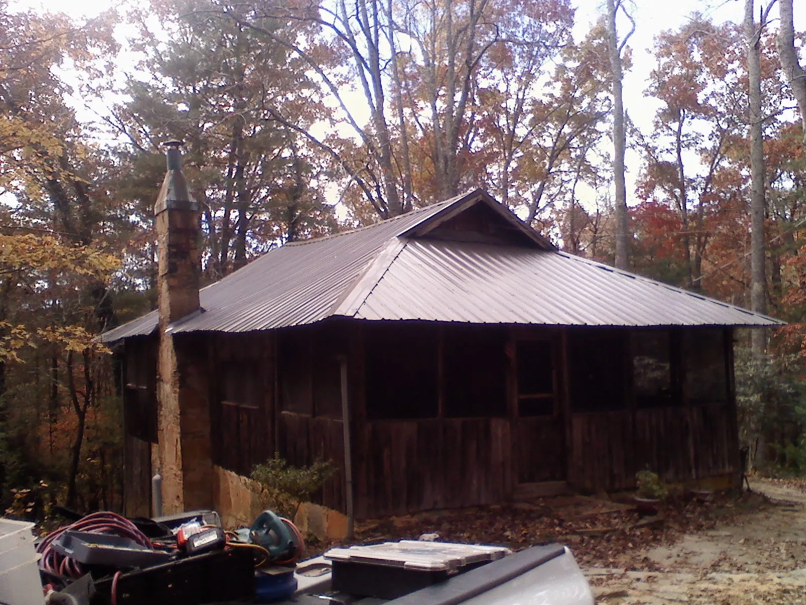 Brown metal hip roof on an old cabin with a stone chimney in Kelso