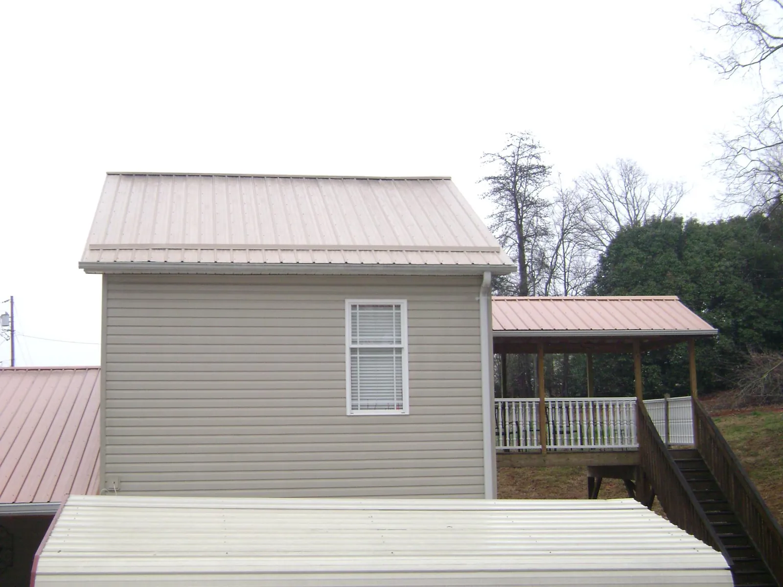 Tan metal roofs on a two story addition and attached porch, from a Roof Replacement job in Kelso